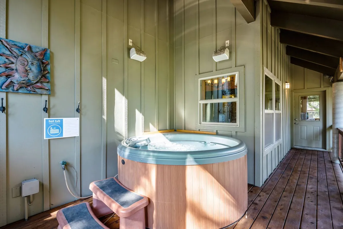 This interior image focuses on a tranquil hot tub space with decorative wall art, warm wooden floors, and windows that let in natural light. The mood is peaceful and restorative, ideal for relaxing after a day on the slopes.