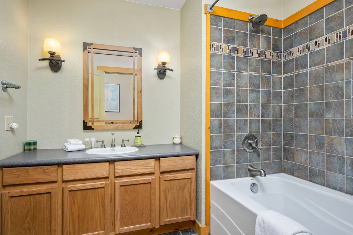 A bright and modern bathroom with a double sink vanity, a large framed mirror, and a bathtub with a shower. The space feels calm and refreshing, ideal for self-care routines and unwinding after a busy day.